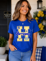 Model wearing a royal blue Hurricanes Varsity H graphic spirit shirt featuring a yellow gingham varsity H with blue star accents.
